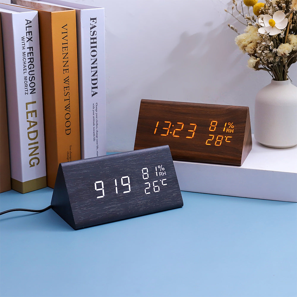 Wooden digital alarm clock with temperature display on a shelf.